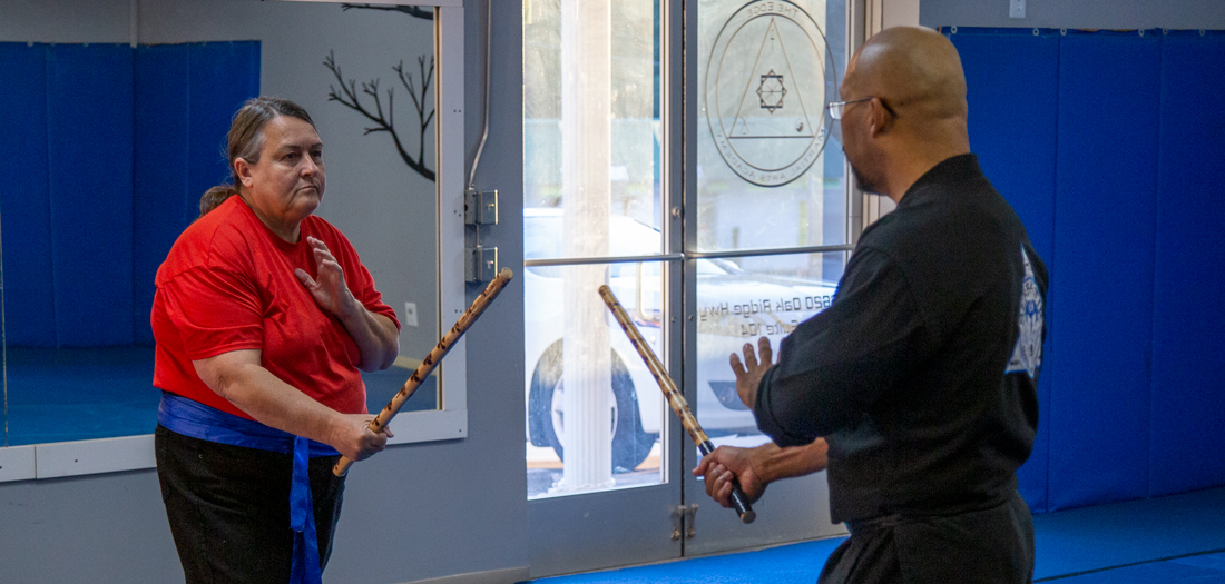 Grandmaster McCleary and a female student using sticks in a martial arts class.